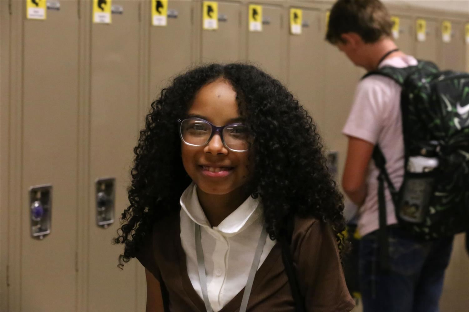 Westridge Middle School African American student smiling in the hallway in front of lockers with a backpack.